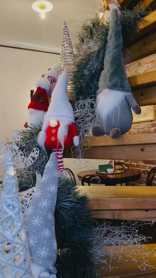 Ziemassvētku rūķi un egļu zari uz koka spirālveida kāpnēm